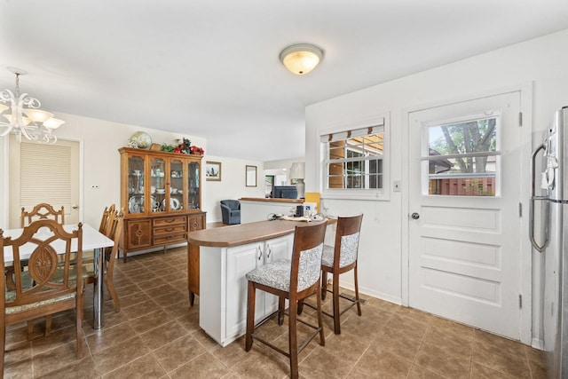 1207 W Busse Ave, Mount Prospect, IL 60056 - kitchen featuring freestanding refrigerator, a chandelier, a peninsula, a breakfast bar area, and decorative light fixtures