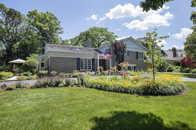100 Beach Rd, Glencoe, IL 60022 - view of front of house featuring a front yard, a chimney, and brick siding