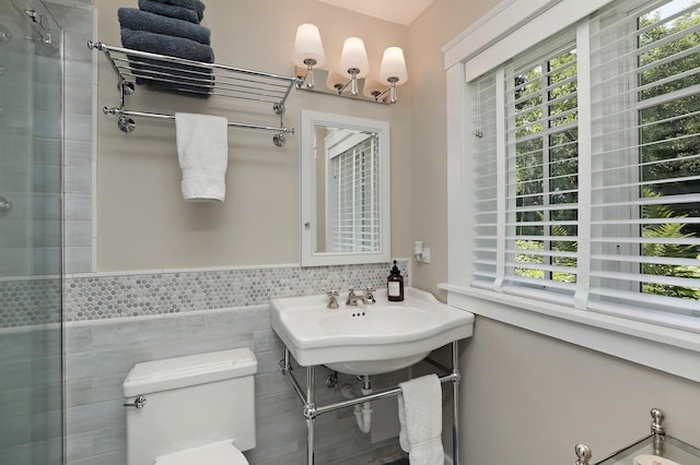 100 Beach Rd, Glencoe, IL 60022 - full bathroom with healthy amount of natural light, a tile shower, a wainscoted wall, and tile walls