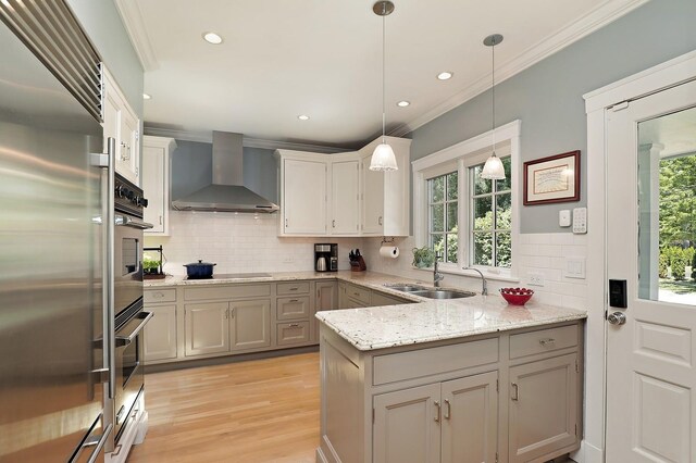 100 Beach Rd, Glencoe, IL 60022 - kitchen with wall chimney exhaust hood, appliances with stainless steel finishes, backsplash, light wood-style flooring, and crown molding