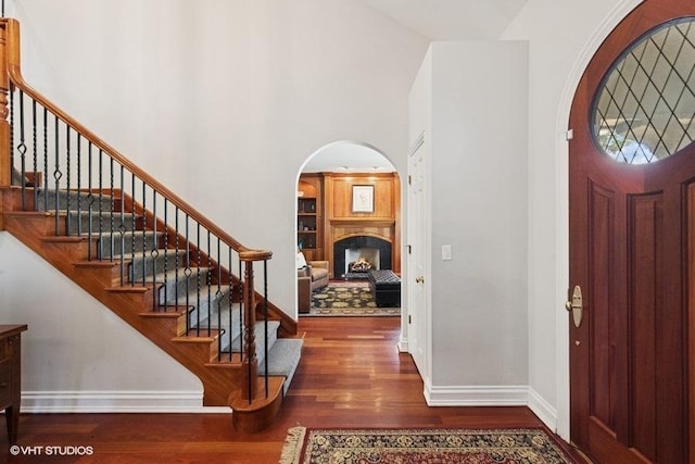 3967 Garden Ave, Western Springs, IL 60558 - entrance foyer with wood finished floors, arched walkways, a towering ceiling, stairs, and a lit fireplace