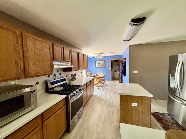 2525 E 6th St, Belvidere, IL 61008 - kitchen featuring stainless steel appliances, under cabinet range hood, brown cabinets, and a kitchen island