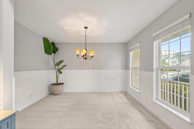 2311 Tremont Ave, Aurora, IL 60502 - unfurnished dining area with a chandelier, light carpet, and a wainscoted wall