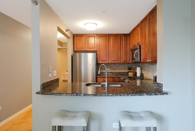 345 N La Salle Dr Unit 1010, Chicago, IL 60654 - kitchen with stainless steel appliances, dark stone counters, decorative backsplash, a peninsula, and light wood-style floors