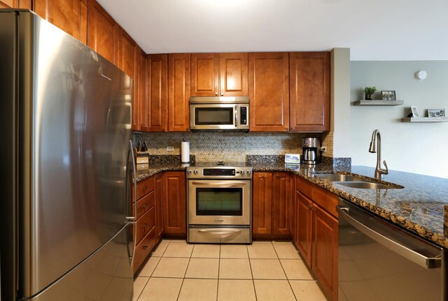 345 N La Salle Dr Unit 1010, Chicago, IL 60654 - kitchen featuring appliances with stainless steel finishes, light tile patterned flooring, decorative backsplash, dark stone countertops, and brown cabinets