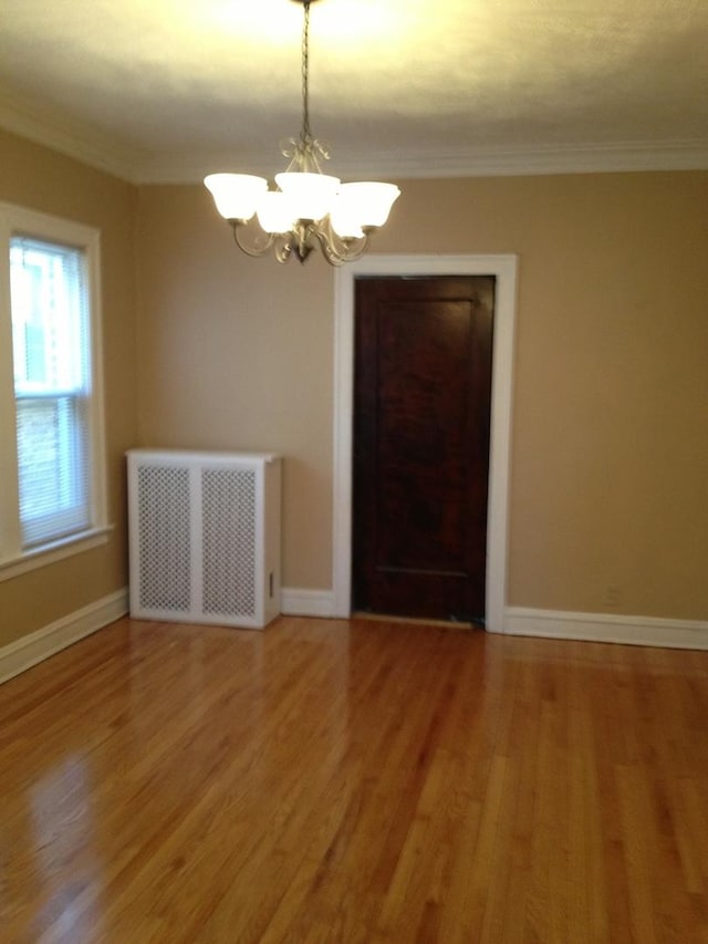 7816 S Indiana Ave, Chicago, IL 60619 - spare room with radiator, a chandelier, light wood-type flooring, and ornamental molding