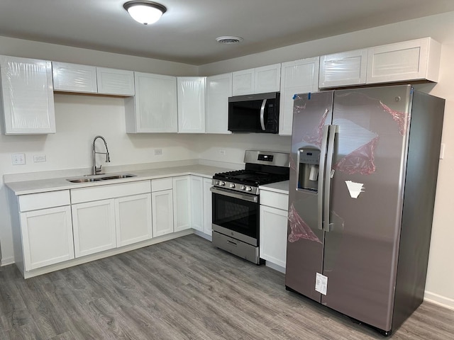 16341 Justine St, Markham, IL 60428 - kitchen featuring appliances with stainless steel finishes, light wood finished floors, light countertops, and white cabinets