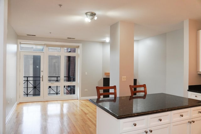 1444 N Orleans St Unit 6E, Chicago, IL 60610 - kitchen featuring light wood-type flooring, dark stone countertops, white cabinetry, and a center island