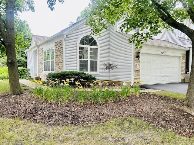 4797 Amber Cir, Hoffman Estates, IL 60192 - view of property exterior featuring stone siding, asphalt driveway, a garage, and roof with shingles