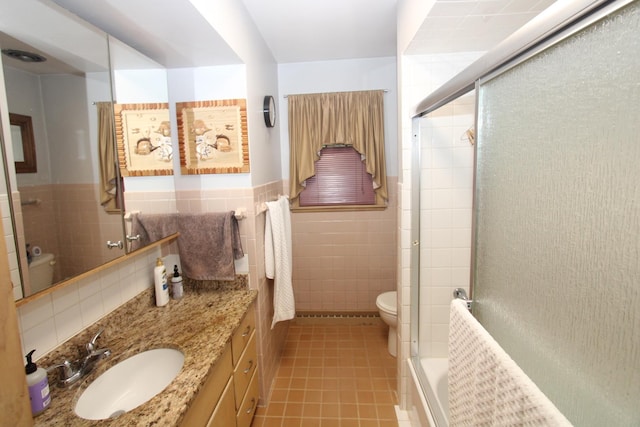 1005 Black Rd, Joliet, IL 60435 - bathroom featuring tile walls, vanity, tile patterned flooring, combined bath / shower with glass door, and a wainscoted wall