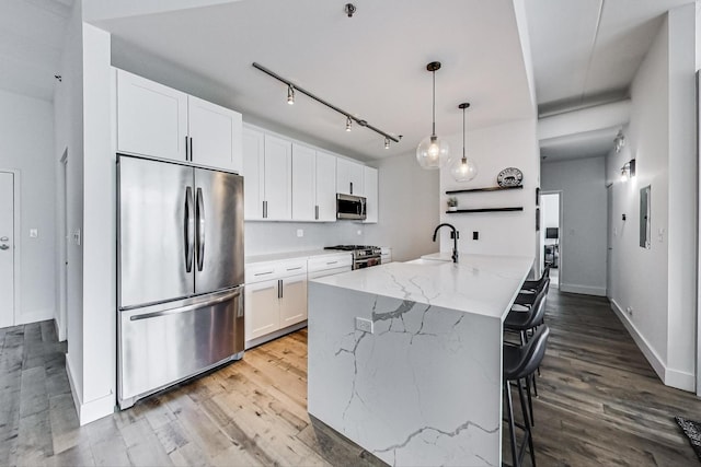 920 W Madison St Unit F8, Chicago, IL 60607 - kitchen featuring stainless steel appliances, white cabinetry, wood finished floors, a kitchen bar, and light stone countertops
