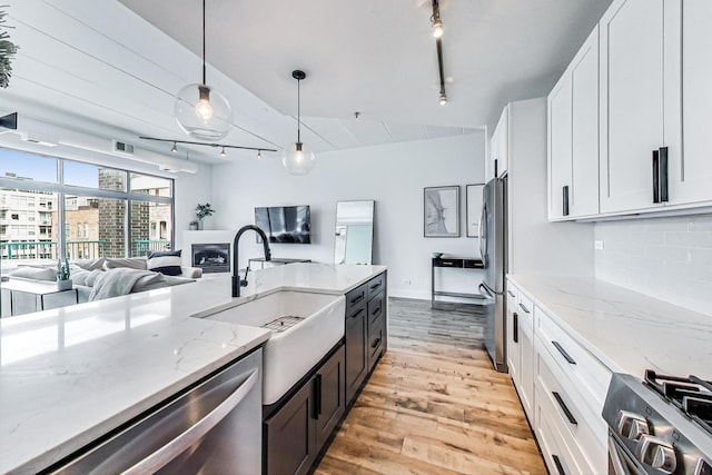 920 W Madison St Unit F8, Chicago, IL 60607 - kitchen featuring track lighting, stainless steel appliances, light wood-style flooring, open floor plan, and tasteful backsplash