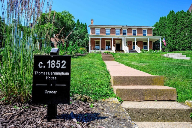 314 Elk St, Galena, IL 61036 - view of front of house featuring brick siding, a porch, a front lawn, and a chimney