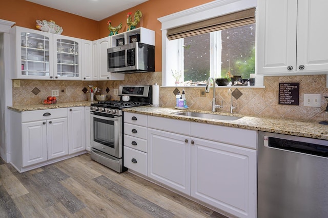 314 Elk St, Galena, IL 61036 - kitchen featuring stainless steel appliances, light wood-style floors, glass insert cabinets, white cabinetry, and decorative backsplash