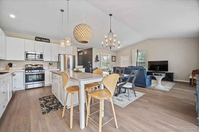 1126 Mandalay Ln Unit 1126, Bolingbrook, IL 60490 - kitchen featuring stainless steel appliances, wood finished floors, vaulted ceiling, a center island, and a chandelier