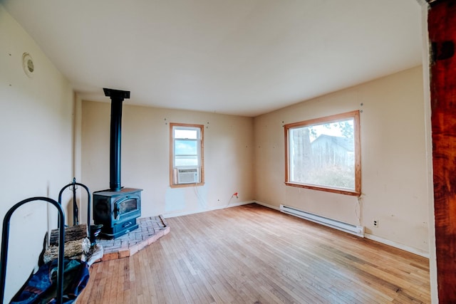 2371 N 3100 E Rd, Donovan, IL 60931 - unfurnished living room with baseboard heating, a wood stove, cooling unit, and hardwood / wood-style flooring
