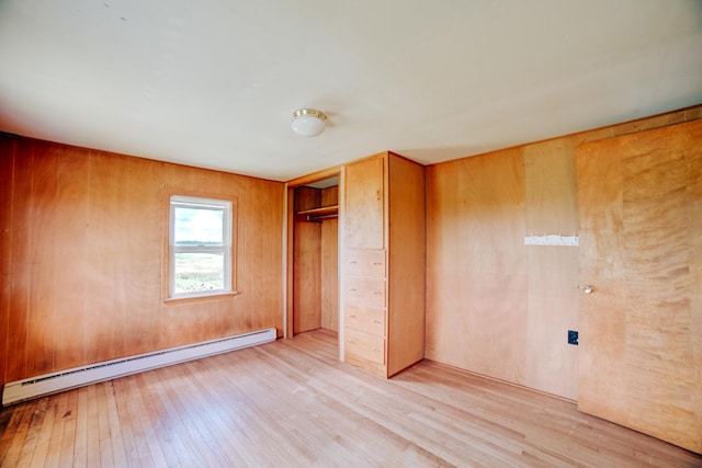 2371 N 3100 E Rd, Donovan, IL 60931 - unfurnished bedroom with baseboard heating, light wood-type flooring, a closet, and wood walls