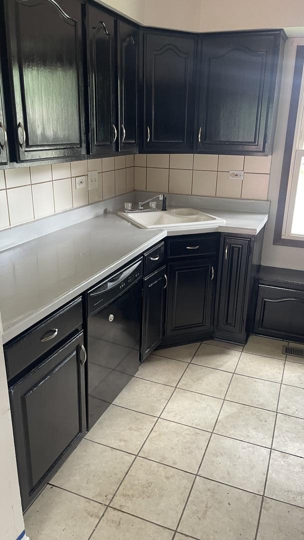 8027 Northway Dr, Hanover Park, IL 60133 - kitchen featuring dishwasher, dark cabinetry, light tile patterned flooring, decorative backsplash, and light countertops