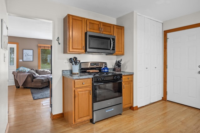 211 David Dr, Streamwood, IL 60107 - kitchen featuring appliances with stainless steel finishes, light wood-type flooring, brown cabinets, dark countertops, and open floor plan