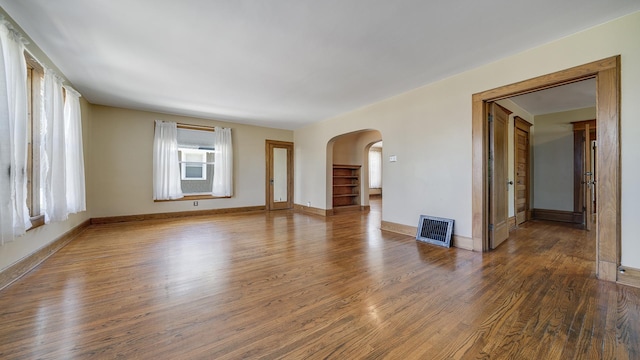 611 S Hennepin Ave, Dixon, IL 61021 - unfurnished living room featuring arched walkways, wood finished floors, and heating unit