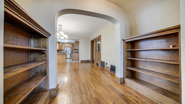 611 S Hennepin Ave, Dixon, IL 61021 - hall with arched walkways, light wood-style floors, and a chandelier