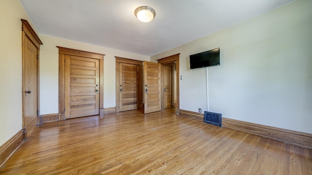 611 S Hennepin Ave, Dixon, IL 61021 - unfurnished bedroom featuring light wood-style flooring and two closets
