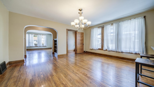 611 S Hennepin Ave, Dixon, IL 61021 - unfurnished room featuring arched walkways, a chandelier, and wood finished floors
