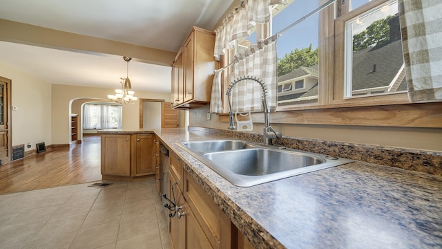 611 S Hennepin Ave, Dixon, IL 61021 - kitchen featuring hanging light fixtures, a peninsula, a chandelier, arched walkways, and light tile patterned floors