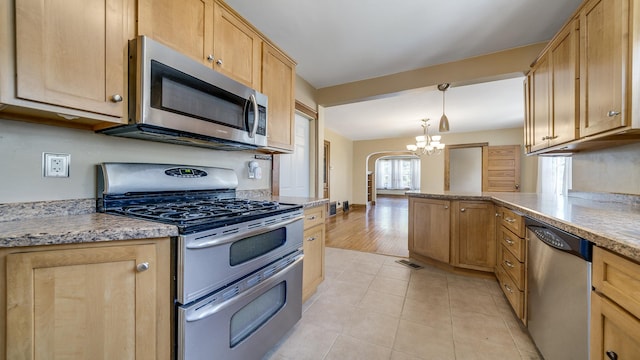 611 S Hennepin Ave, Dixon, IL 61021 - kitchen with appliances with stainless steel finishes, a chandelier, arched walkways, light tile patterned floors, and a peninsula