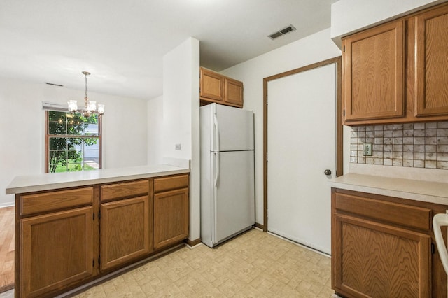 2S772 Timber Dr, Warrenville, IL 60555 - kitchen featuring freestanding refrigerator, a peninsula, brown cabinetry, light flooring, and light countertops