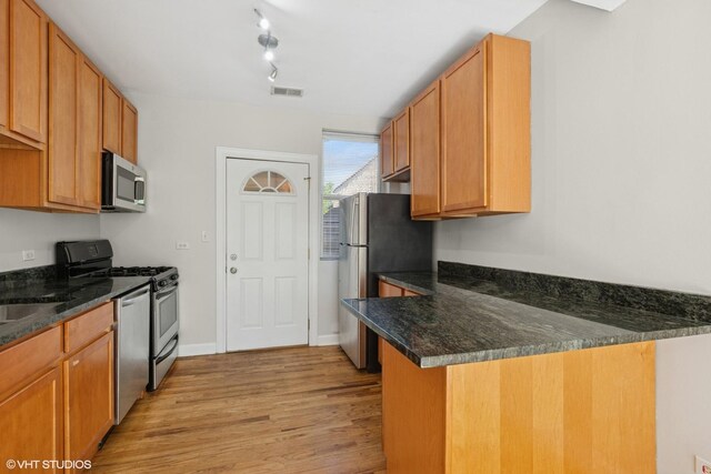 4610 N Monticello Ave Unit 3E, Chicago, IL 60625 - kitchen featuring stainless steel appliances, light wood finished floors, a peninsula, and dark stone countertops