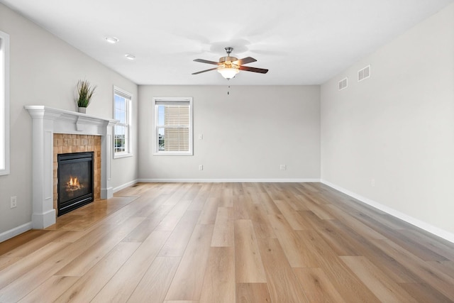 1312 Wicklow Dr, Bloomington, IL 61705 - unfurnished living room featuring light wood-style flooring, ceiling fan, and a tiled fireplace