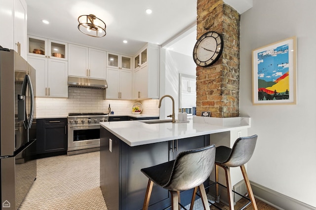 5729 S Harper Ave, Chicago, IL 60637 - kitchen with appliances with stainless steel finishes, under cabinet range hood, a breakfast bar area, backsplash, and glass insert cabinets