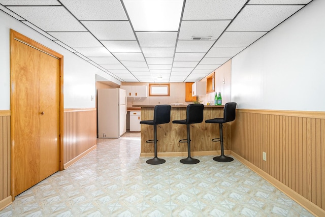 5401 S Nagle Ave, Chicago, IL 60638 - kitchen with freestanding refrigerator, a peninsula, a wainscoted wall, light flooring, and a kitchen bar
