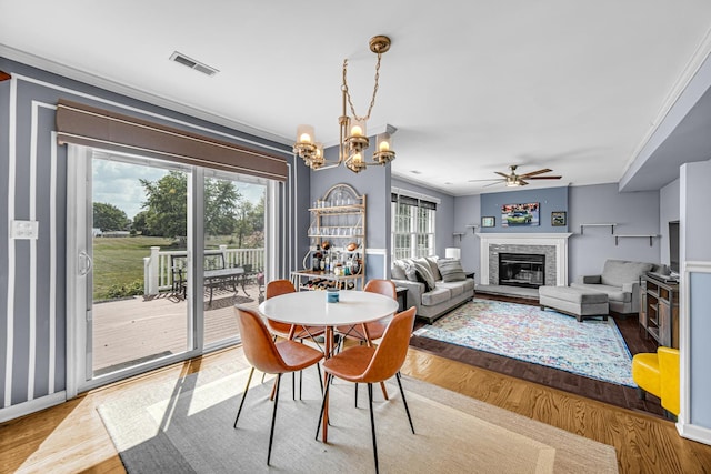 26711 S Greenbriar Dr, Monee, IL 60449 - dining space with wood finished floors, a ceiling fan, a glass covered fireplace, a chandelier, and crown molding