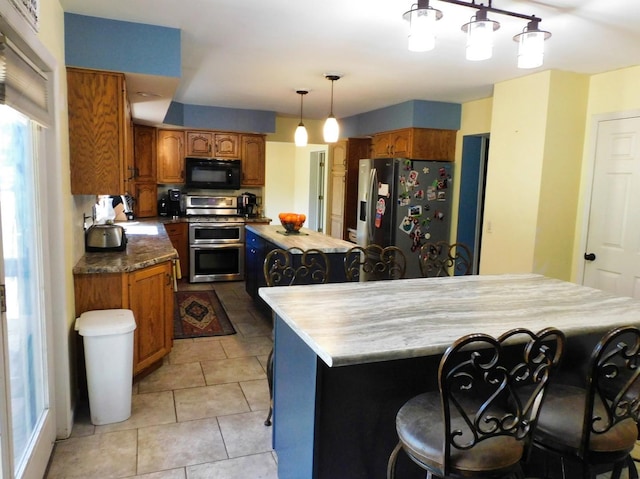 565 Sandra Cir, Freeport, IL 61032 - kitchen with stainless steel appliances, a kitchen island, brown cabinetry, a kitchen breakfast bar, and light tile patterned flooring