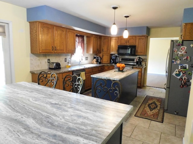 565 Sandra Cir, Freeport, IL 61032 - kitchen with stainless steel appliances, a kitchen island, brown cabinets, decorative light fixtures, and decorative backsplash