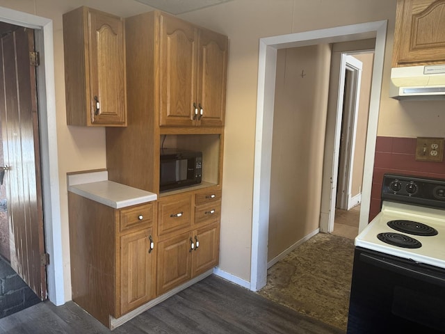 614 N Jackson St, Clinton, IL 61727 - kitchen with electric range, black microwave, exhaust hood, light countertops, and dark wood finished floors