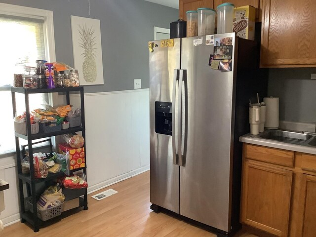 427 Kenyon Ave, Romeoville, IL 60446 - kitchen with stainless steel refrigerator with ice dispenser, plenty of natural light, wainscoting, light wood-style floors, and light countertops