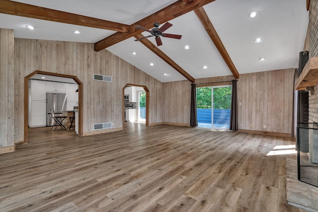 746 Old Stage Rd, Morris, IL 60450 - unfurnished living room with arched walkways, a large fireplace, wood walls, ceiling fan, and wood finished floors