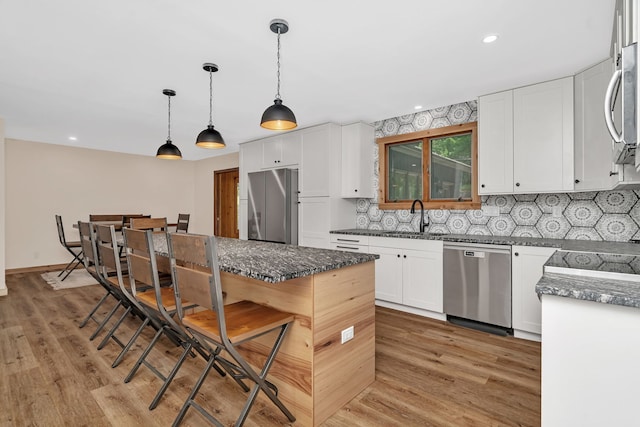 746 Old Stage Rd, Morris, IL 60450 - kitchen featuring stainless steel appliances, white cabinets, a breakfast bar, tasteful backsplash, and a kitchen island
