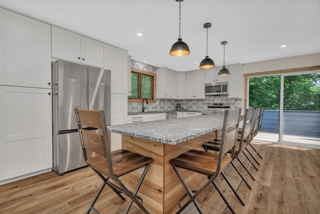 746 Old Stage Rd, Morris, IL 60450 - kitchen with appliances with stainless steel finishes, light wood-type flooring, backsplash, a kitchen breakfast bar, and white cabinetry