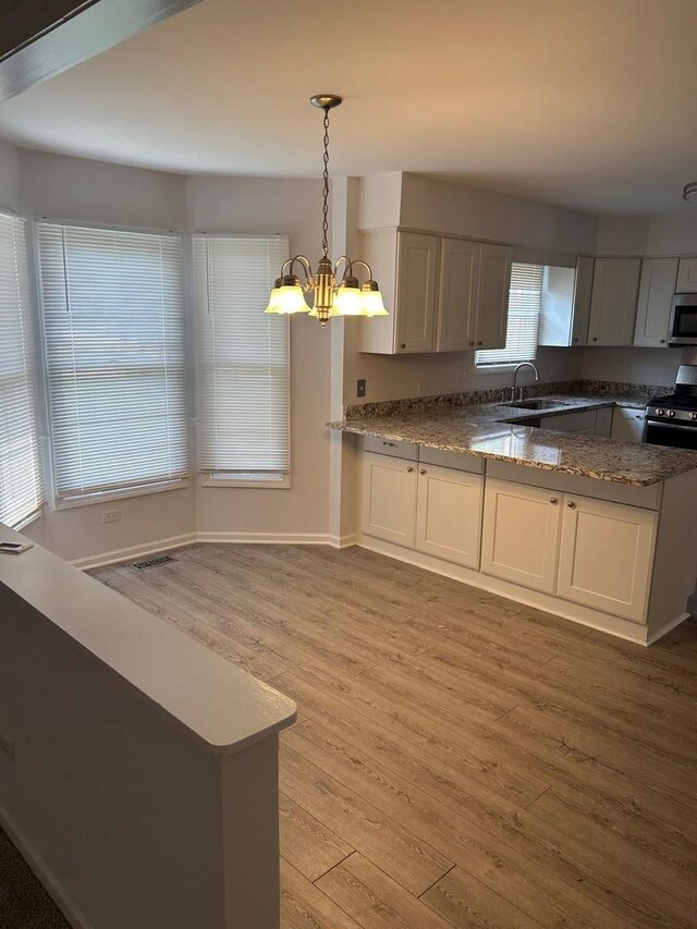 105 Golf View Cir, Prospect Heights, IL 60070 - kitchen featuring stainless steel appliances, light wood-style flooring, a chandelier, a peninsula, and dark stone counters