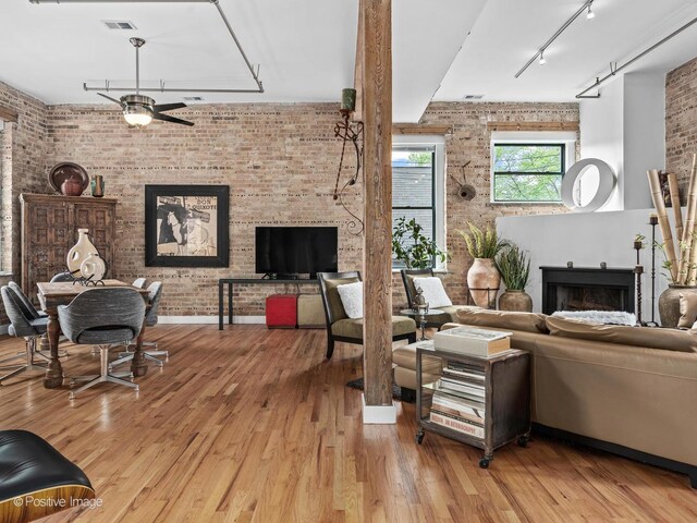 2035 W Charleston St Unit 205, Chicago, IL 60647 - living room featuring brick wall, rail lighting, ceiling fan, a fireplace, and wood finished floors