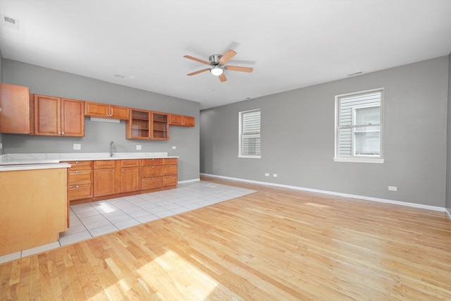 6139 S King Dr, Chicago, IL 60637 - kitchen featuring light wood-type flooring, a ceiling fan, light countertops, and brown cabinets