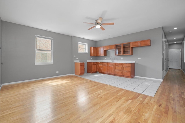 6139 S King Dr, Chicago, IL 60637 - kitchen with light wood-style flooring, ceiling fan, brown cabinets, light countertops, and glass insert cabinets
