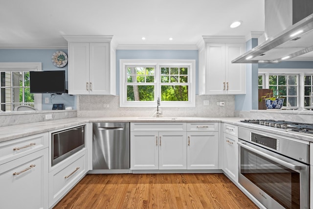 95 Warrington Dr, Lake Bluff, IL 60044 - kitchen with appliances with stainless steel finishes, wall chimney range hood, crown molding, white cabinetry, and decorative backsplash