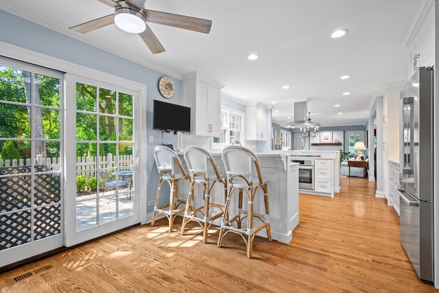 95 Warrington Dr, Lake Bluff, IL 60044 - kitchen with appliances with stainless steel finishes, a peninsula, ornamental molding, light wood-style flooring, and white cabinets