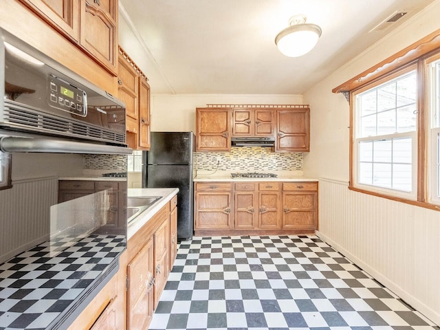 218 Chestnut St, Earlville, IL 60518 - kitchen with freestanding refrigerator, under cabinet range hood, dark flooring, tasteful backsplash, and light countertops