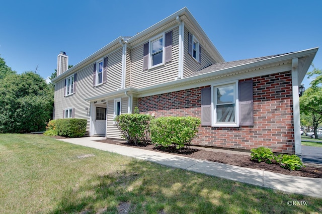 1869 Pebble Beach Cir Unit A, Elk Grove Village, IL 60007 - view of front of house with a chimney, a front lawn, and brick siding